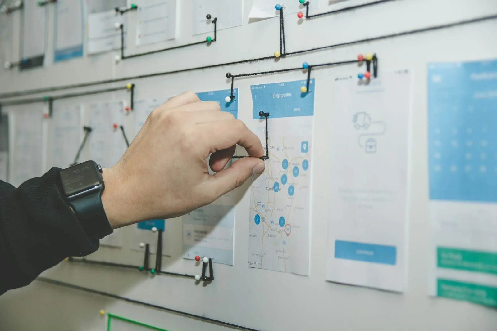 A hand pinning a process diagram to a planning board.